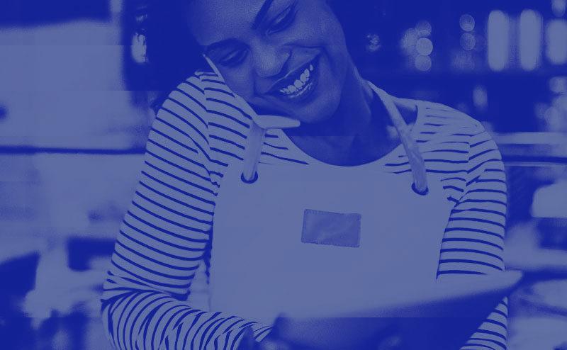 Black woman laughing on the phone and working on tablet