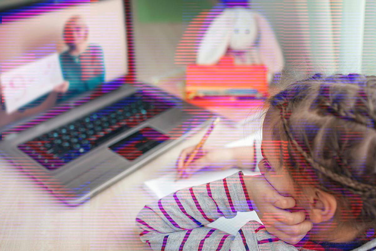 Little girl sitting at desk taking class online