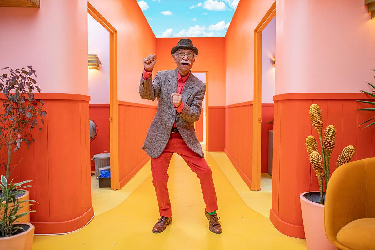 Elderly man in colorful outfit dancing in office