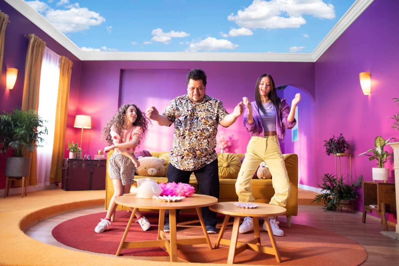 Family dancing in colorful living room with blue sky overhead