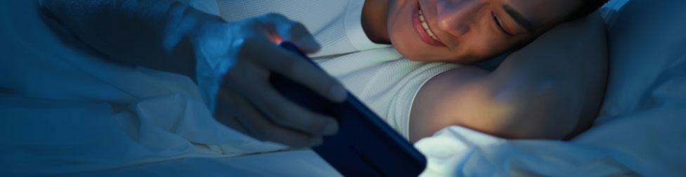 Person smiling at phone lying in bed