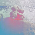 Colorized image of two teddy bears hugging with a wave of water