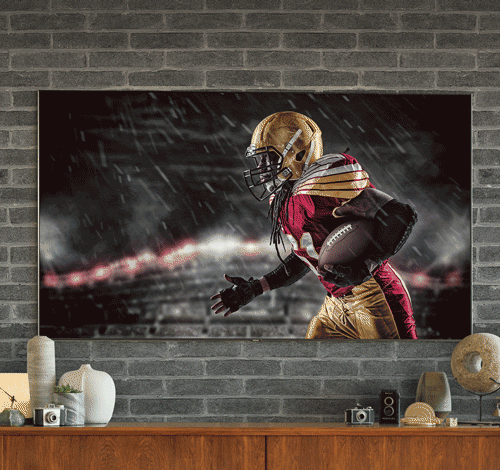 TV on gray brick wall showing football image