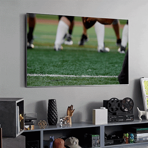 TV on wall showing video of kicking a football