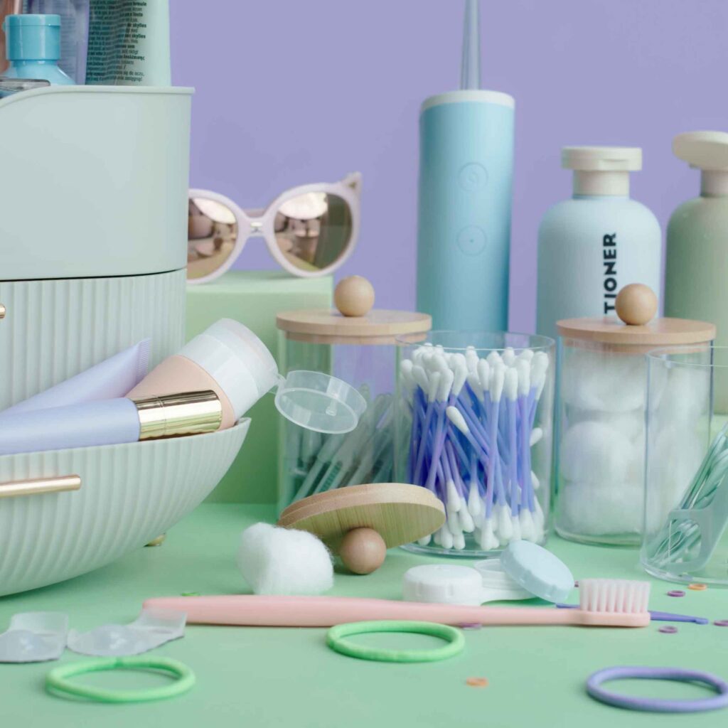 A collection of bathroom essentials, including cotton swabs, lotion bottles, a toothbrush, and toothpaste—styled on pastel green and purple—inspired by Delta Dental digital marketing for a fresh start to your daily routine.