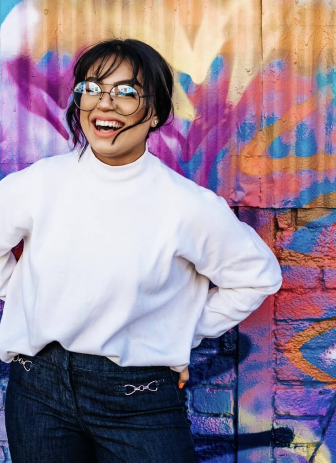 Smiling woman with glasses in front of colorful wall