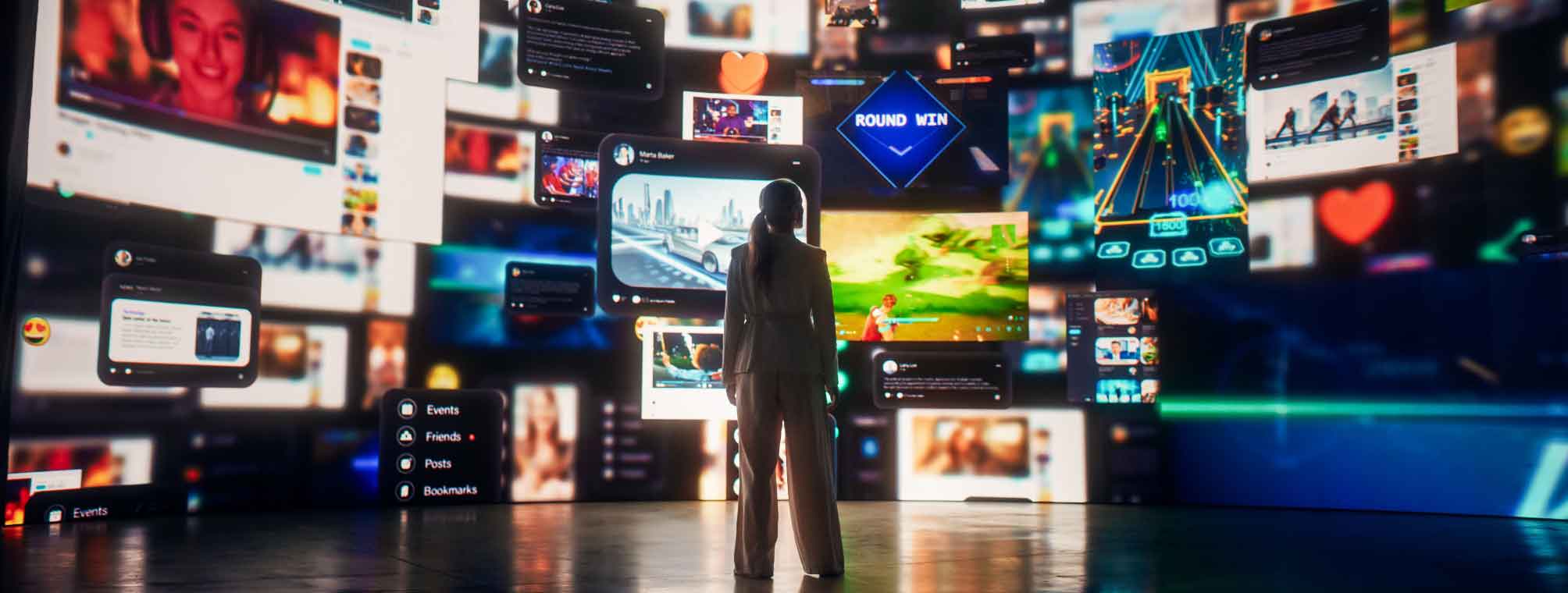 A person stands in a dark room surrounded by large, floating digital screens displaying various images, social media posts, videos, and icons, creating an immersive, high-tech environment.