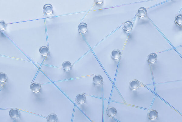 Clear glass cups are arranged on a light surface, connected by intersecting iridescent plastic straws, creating a network-like pattern across the image—reminiscent of how SEO for AI answer engines links information seamlessly.
