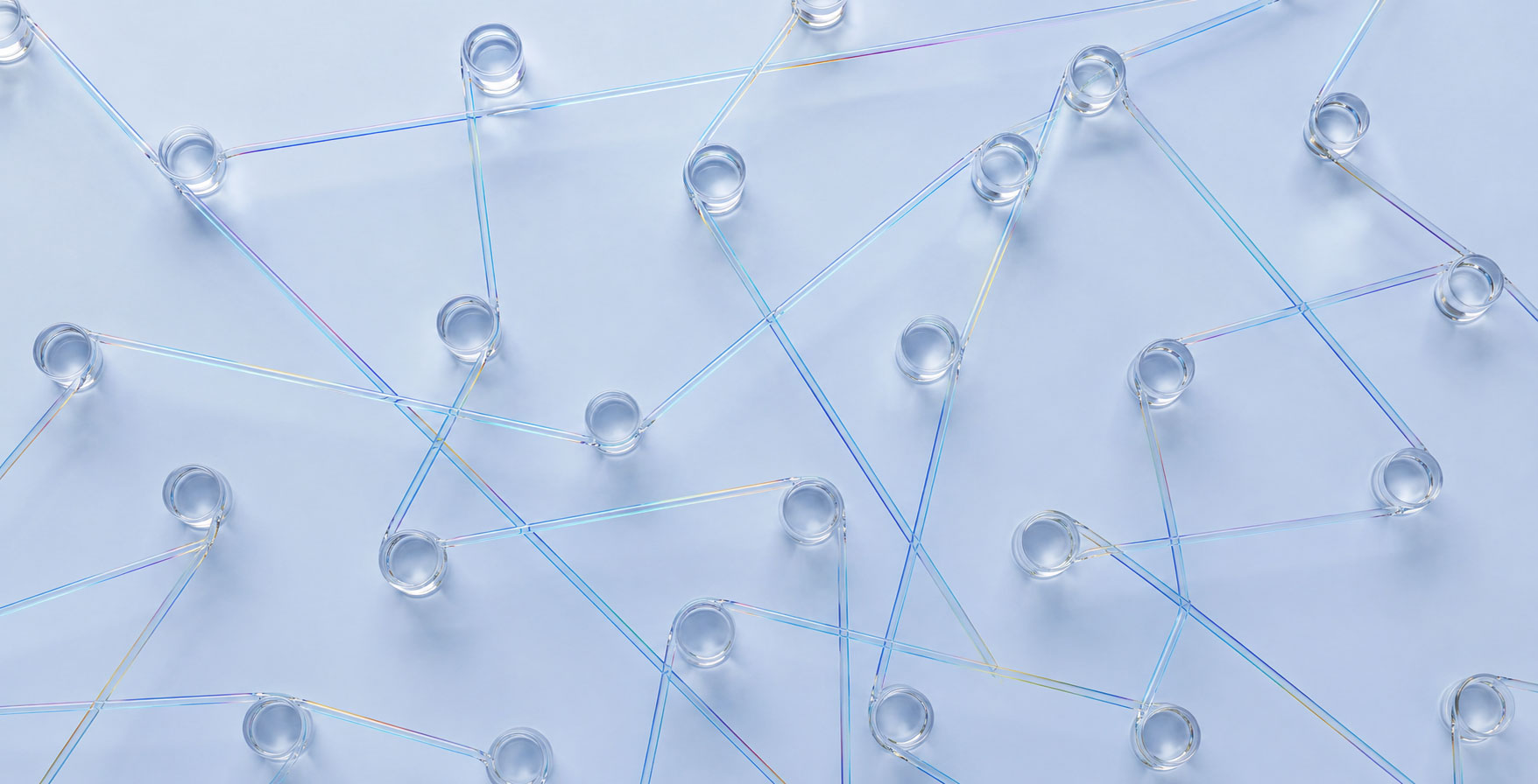 Clear glass cups are arranged on a light surface, connected by intersecting iridescent plastic straws, creating a network-like pattern across the image—reminiscent of how SEO for AI answer engines links information seamlessly.