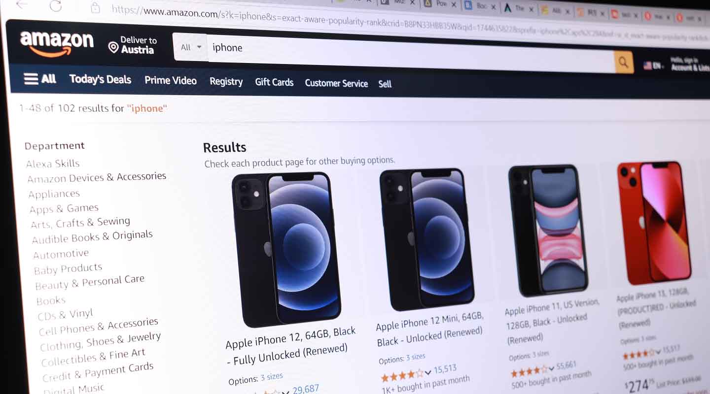 A computer screen displays Amazon's search results for iPhone, showing listings for various Apple iPhone models, including images, prices, and brief product details—demonstrating how SEO for AI answer engines helps optimize product visibility. Multiple browser tabs are visible at the top.