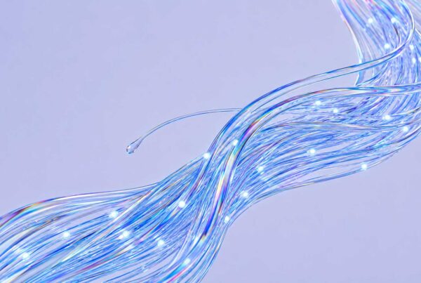 A bundle of glowing, translucent fiber optic cables curves against a light purple background, emitting blue and white light points along their strands—evoking the seamless connectivity and innovation powering agentic commerce for brands.